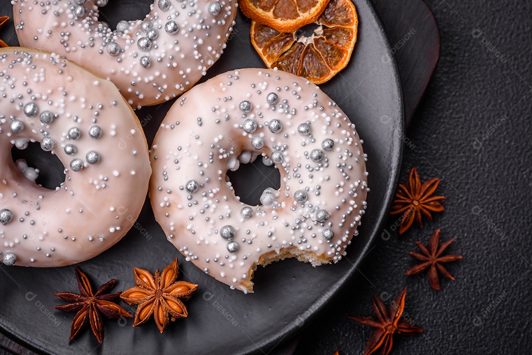 Delicioso donut fresco de cor branca ou bege com contas prateadas e creme sobre um fundo escuro de concreto