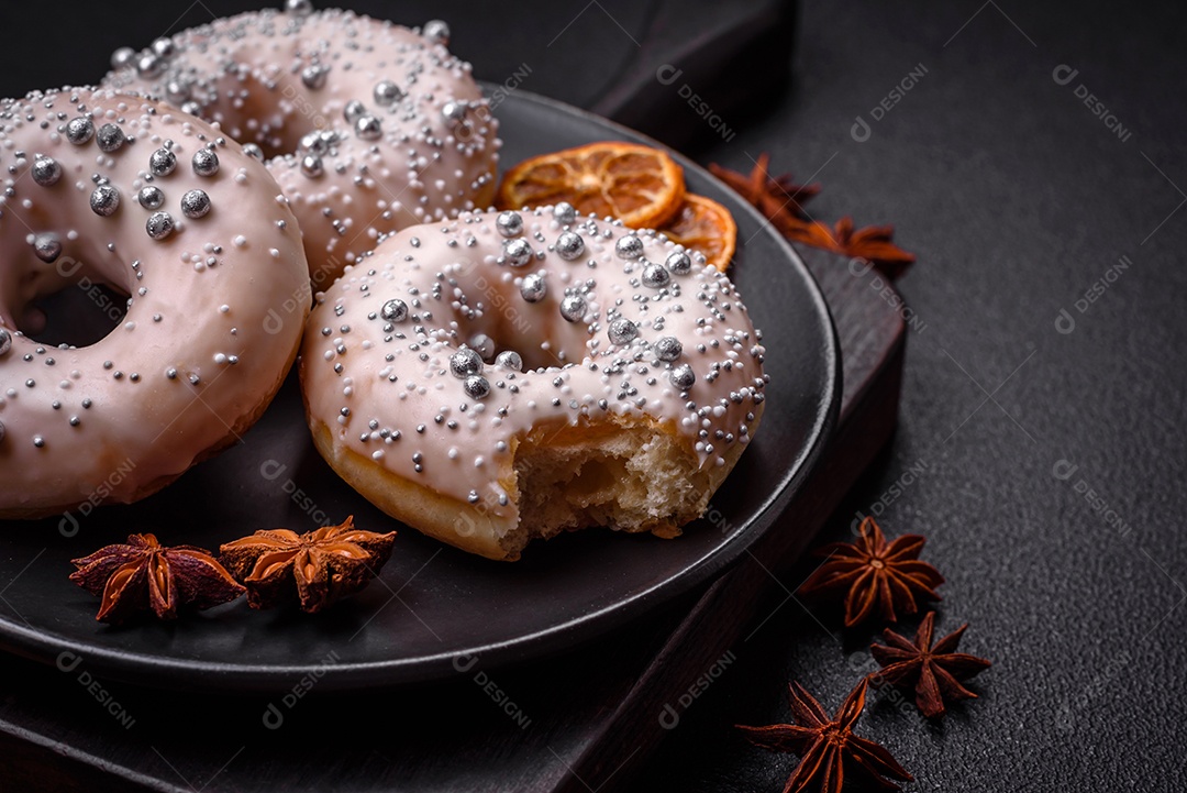 Delicioso donut fresco de cor branca ou bege com contas prateadas e creme sobre um fundo escuro de concreto