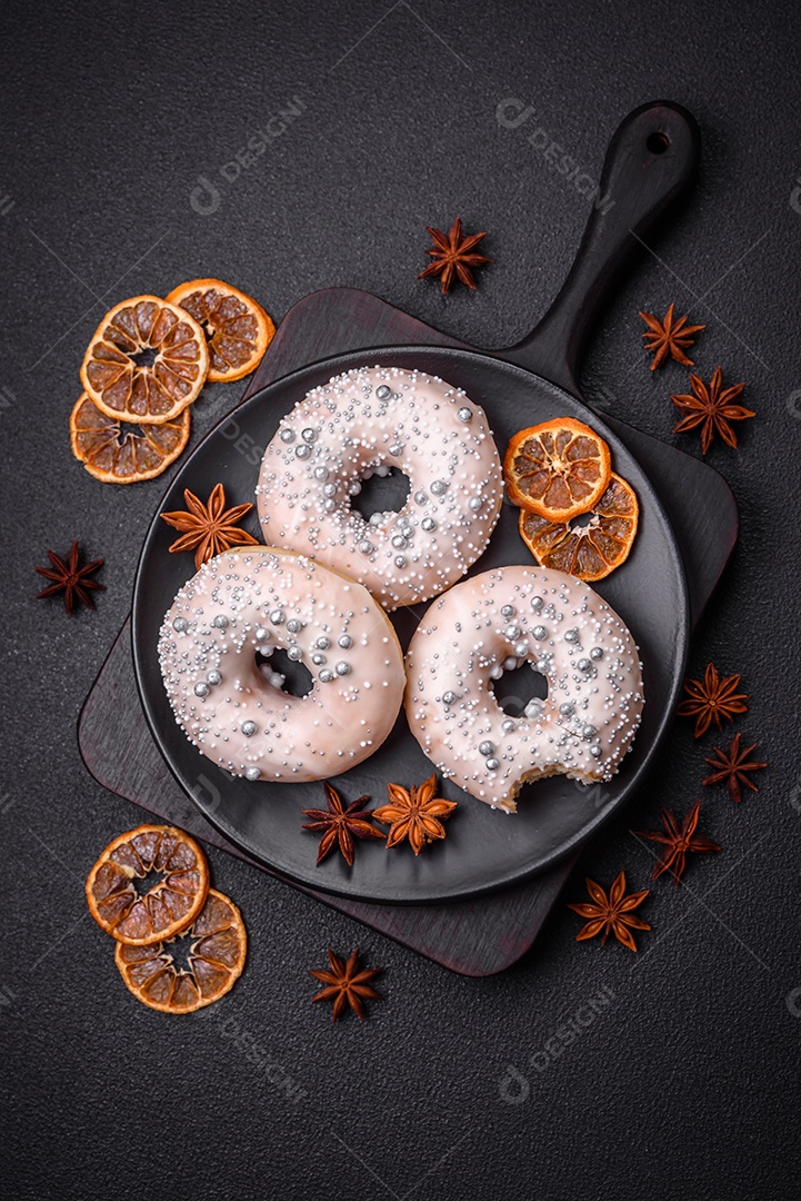 Delicioso donut fresco de cor branca ou bege com contas prateadas e creme sobre um fundo escuro de concreto