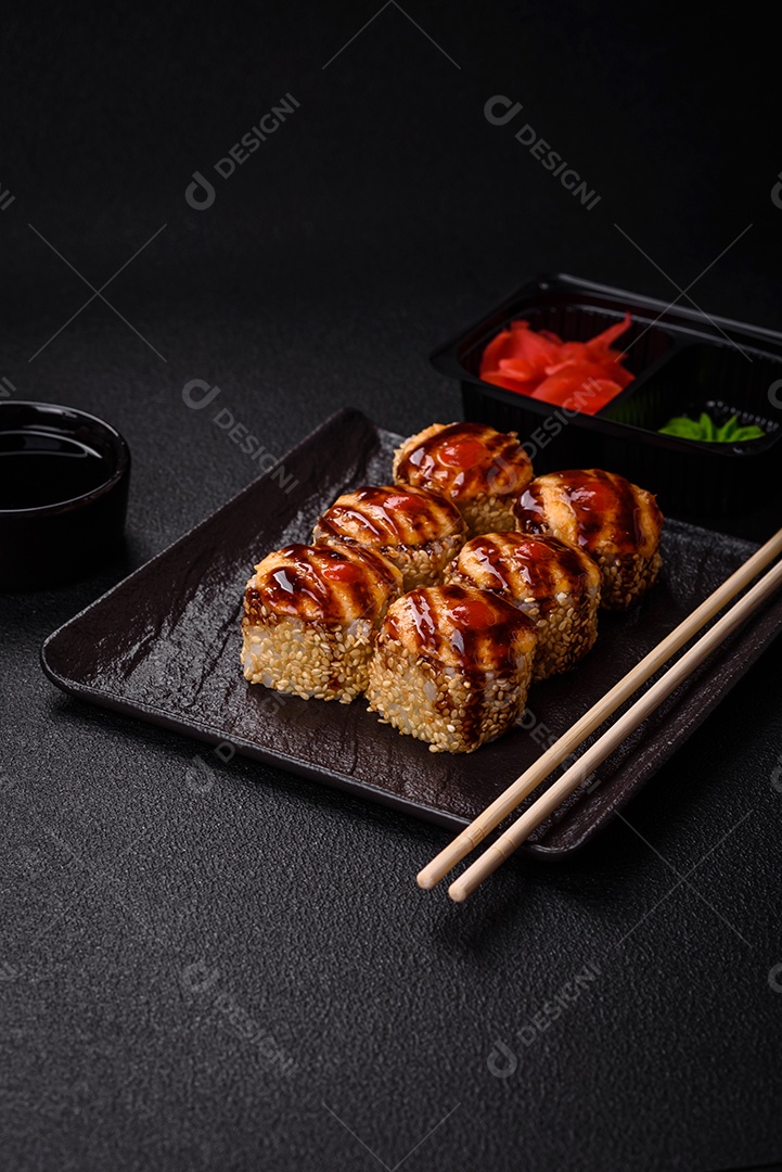 Rolo de sushi quente delicioso com atum, salmão, camarão, pepino e cream cheese em um fundo escuro de concreto