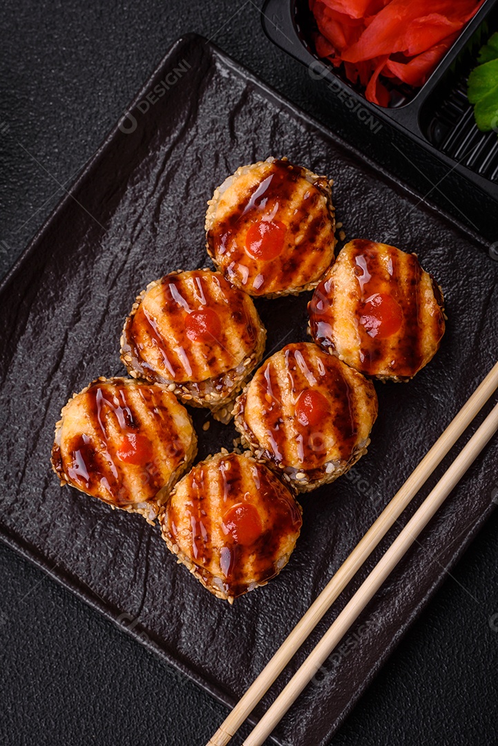 Rolo de sushi quente delicioso com atum, salmão, camarão, pepino e cream cheese em um fundo escuro de concreto