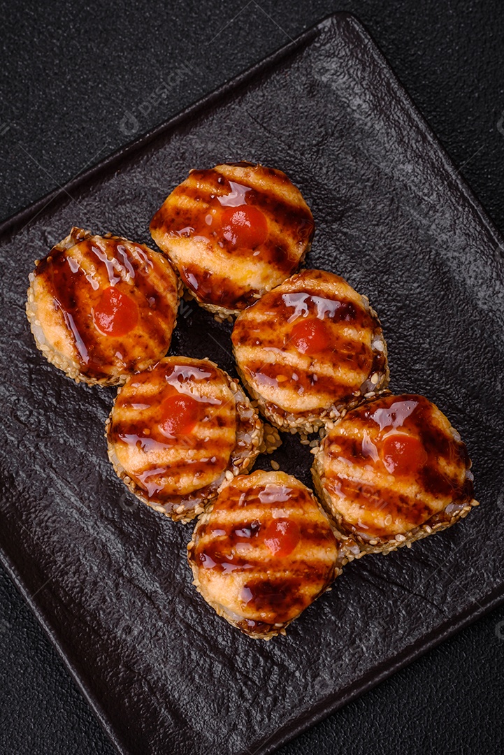 Rolo de sushi quente delicioso com atum, salmão, camarão, pepino e cream cheese em um fundo escuro de concreto