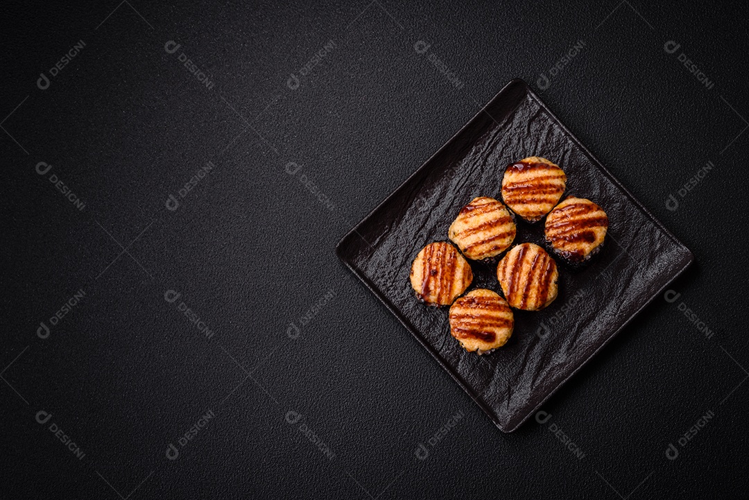 Rolo de sushi quente delicioso com atum, salmão, camarão, pepino e cream cheese em um fundo escuro de concreto