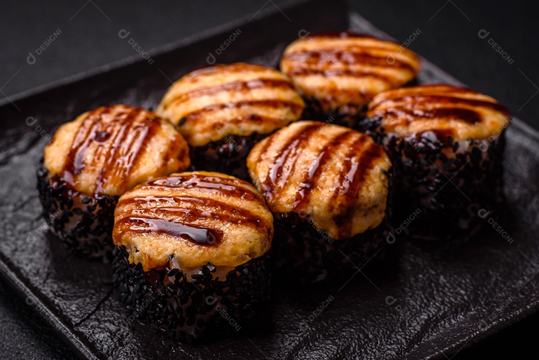 Rolo de sushi quente delicioso com atum, salmão, camarão, pepino e cream cheese em um fundo escuro de concreto