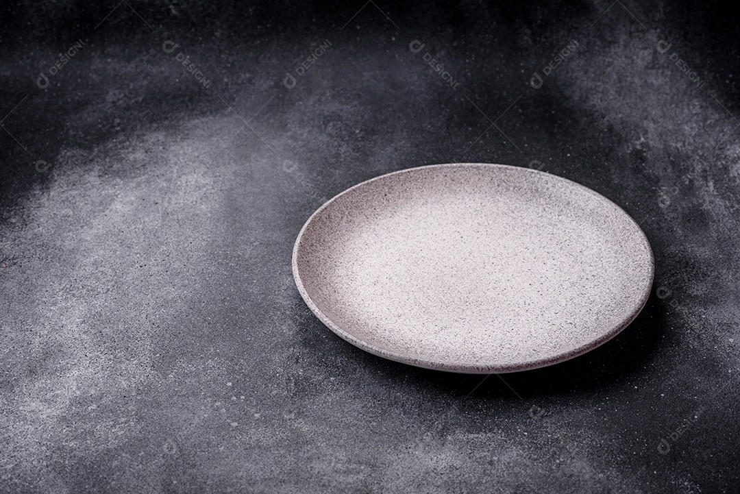 Placa cerâmica redonda vazia como um item de utensílios de cozinha sobre um fundo de concreto texturizado