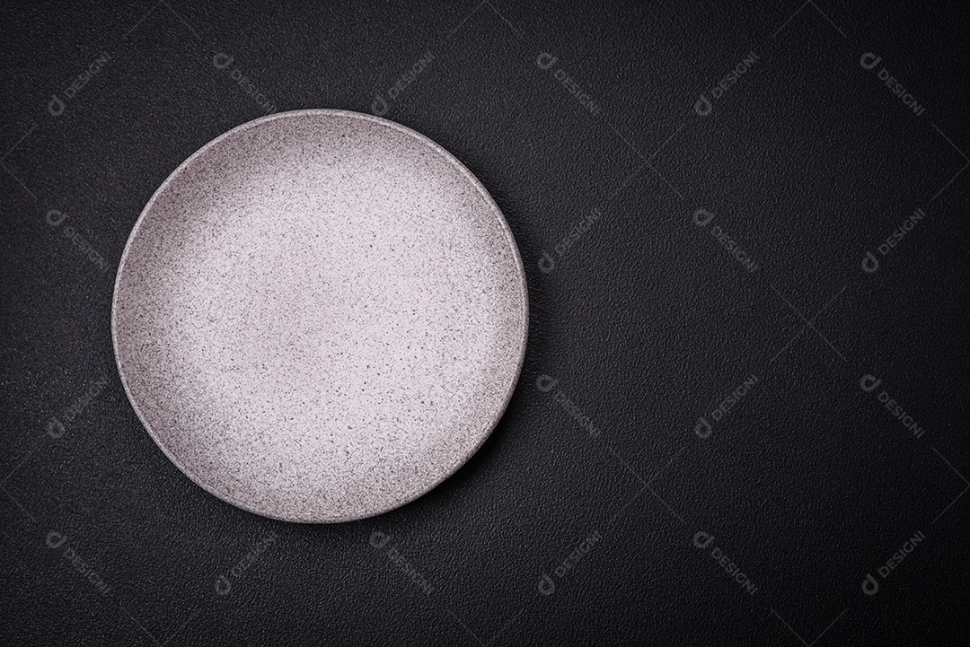 Placa cerâmica redonda vazia como um item de utensílios de cozinha sobre um fundo de concreto texturizado