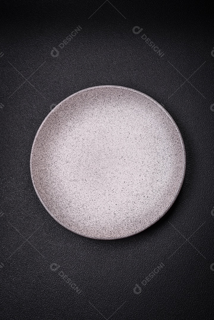 Placa cerâmica redonda vazia como um item de utensílios de cozinha sobre um fundo de concreto texturizado