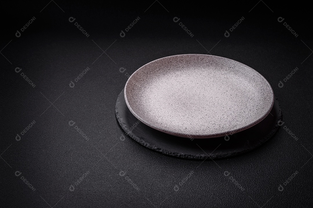 Placa cerâmica redonda vazia como um item de utensílios de cozinha sobre um fundo de concreto texturizado