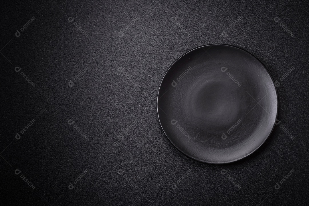 Placa cerâmica vazia e acidentada em um fundo de concreto texturizado. Utensílio de cozinha