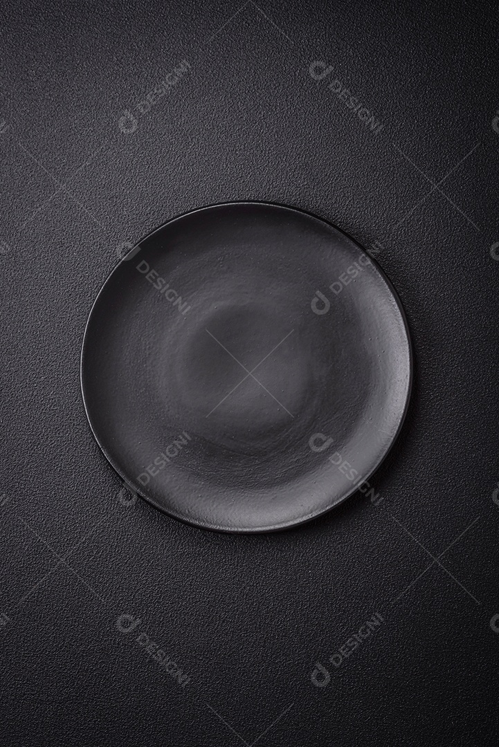 Placa cerâmica vazia e acidentada em um fundo de concreto texturizado. Utensílio de cozinha