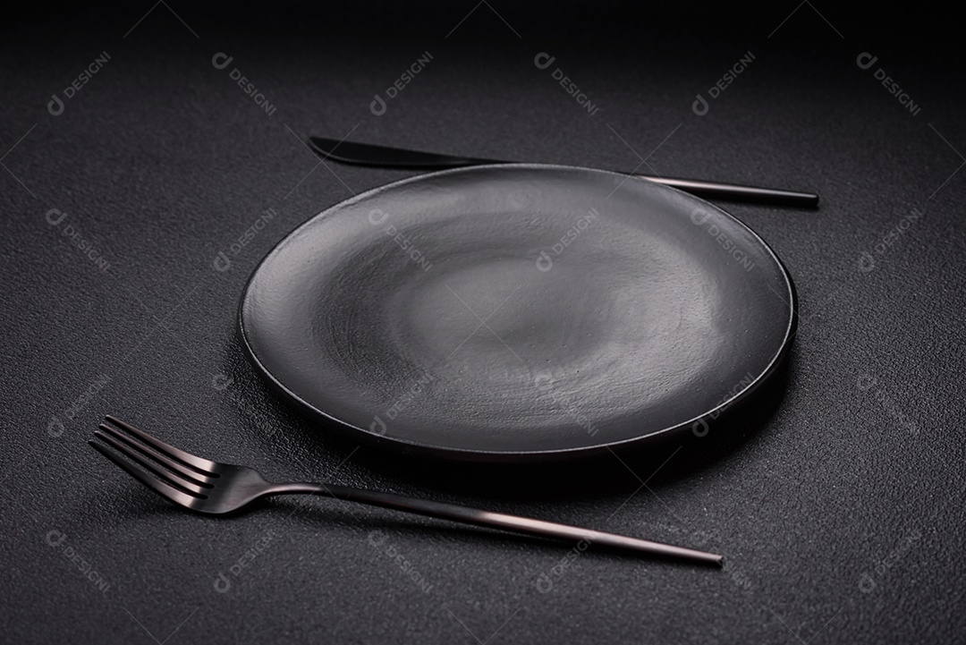 Placa cerâmica vazia e acidentada em um fundo de concreto texturizado. Utensílio de cozinha