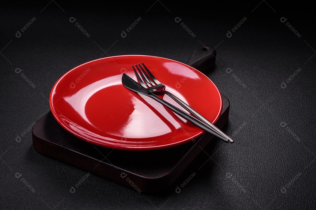 Placa cerâmica vazia e acidentada em um fundo de concreto texturizado. Utensílio de cozinha