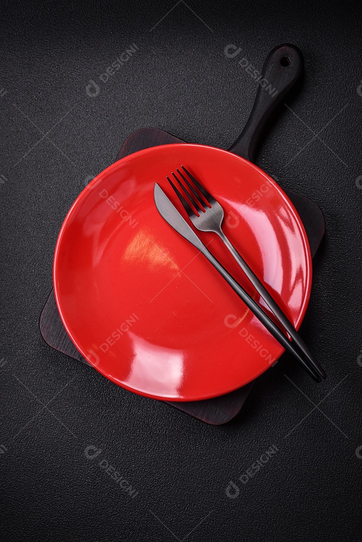 Placa cerâmica vazia e acidentada em um fundo de concreto texturizado. Utensílio de cozinha