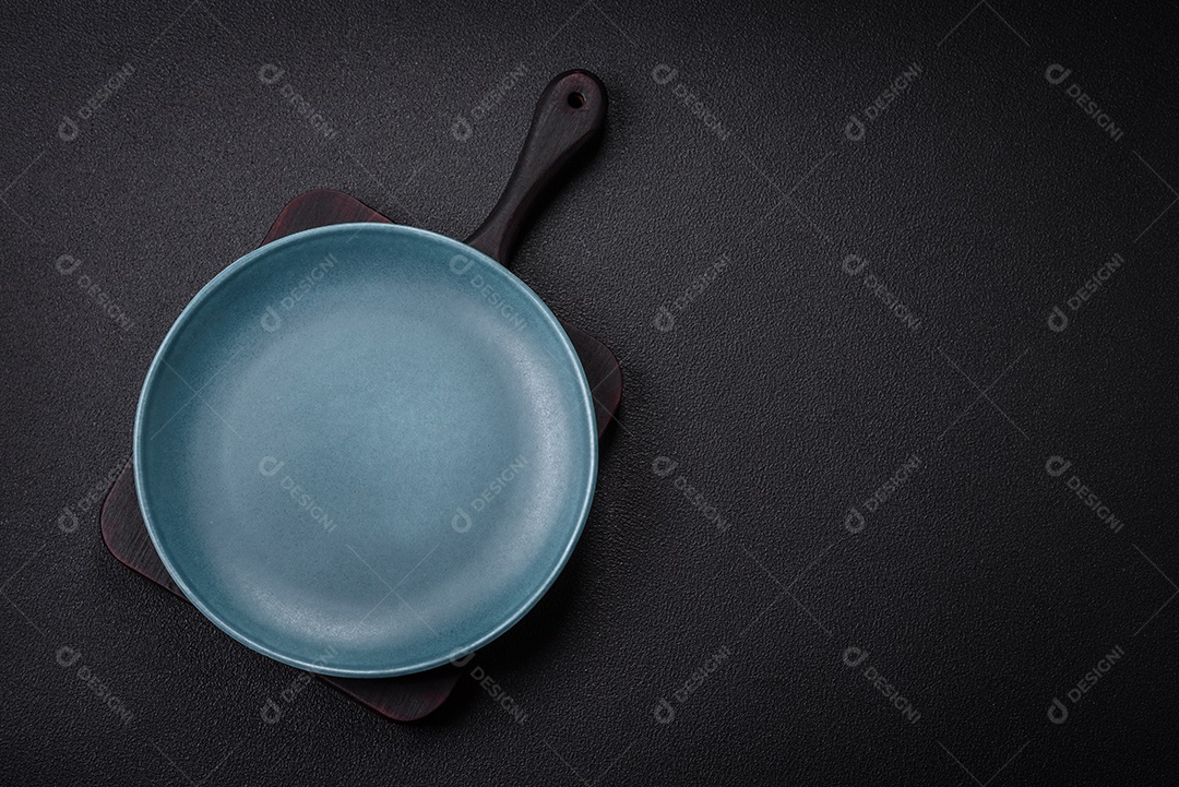 Placa cerâmica vazia e acidentada em um fundo de concreto texturizado. Utensílio de cozinha