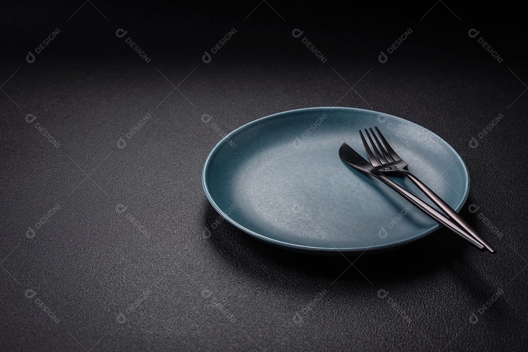 Placa cerâmica vazia e acidentada em um fundo de concreto texturizado. Utensílio de cozinha