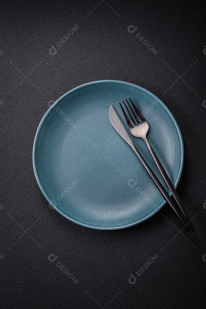 Placa cerâmica vazia e acidentada em um fundo de concreto texturizado. Utensílio de cozinha