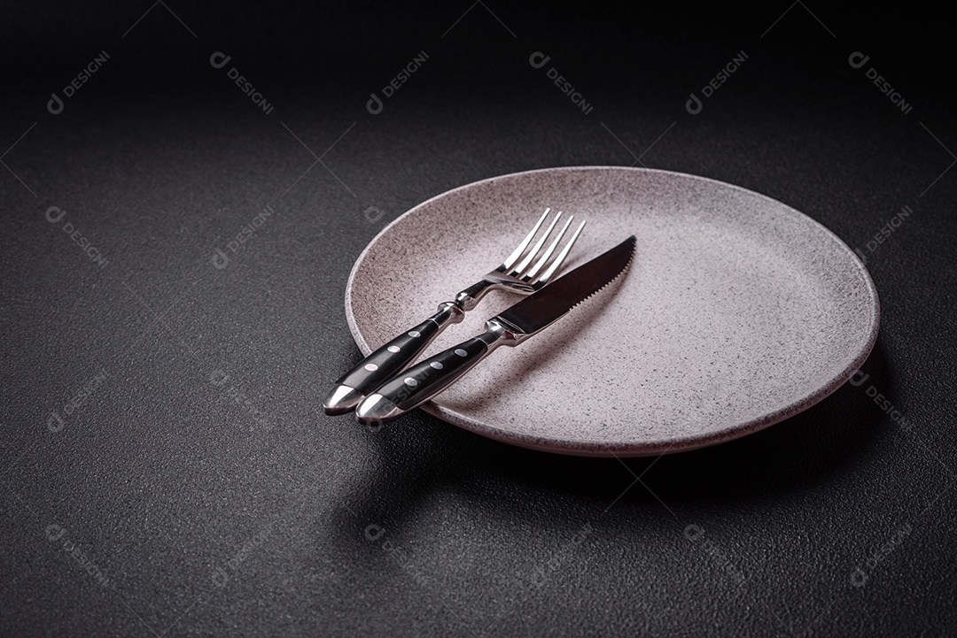 Placa cerâmica vazia e acidentada em um fundo de concreto texturizado. Utensílio de cozinha