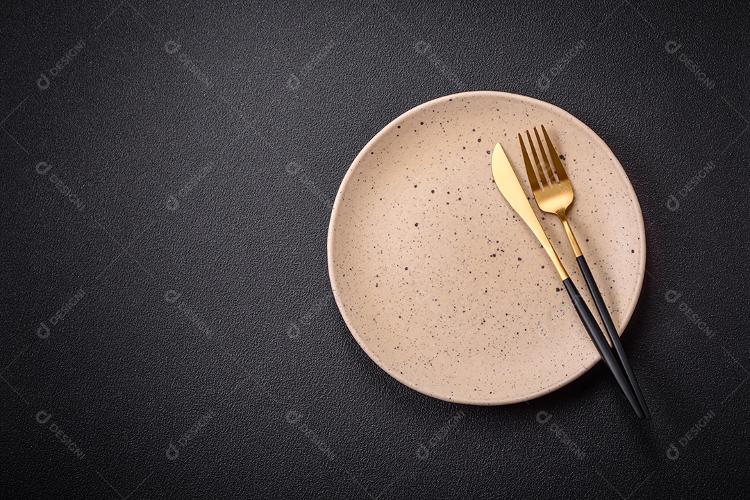 Placa cerâmica vazia e acidentada em um fundo de concreto texturizado. Utensílio de cozinha