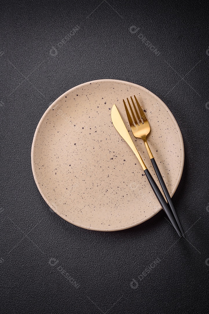 Placa cerâmica vazia e acidentada em um fundo de concreto texturizado. Utensílio de cozinha