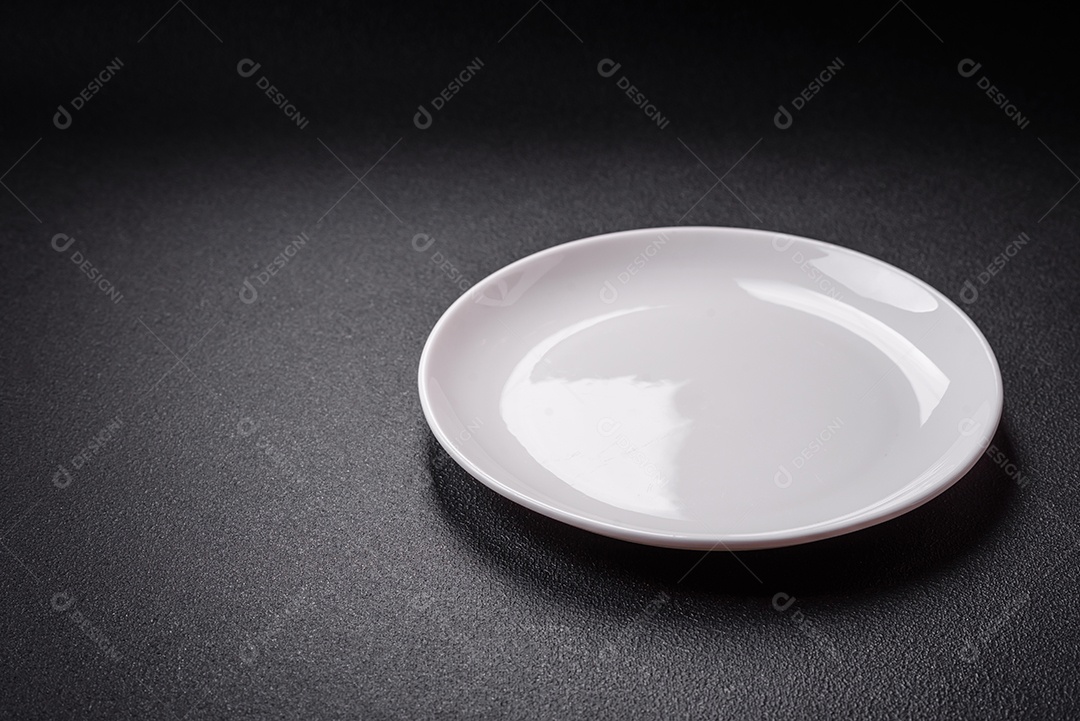 Placa cerâmica vazia e acidentada em um fundo de concreto texturizado. Utensílio de cozinha