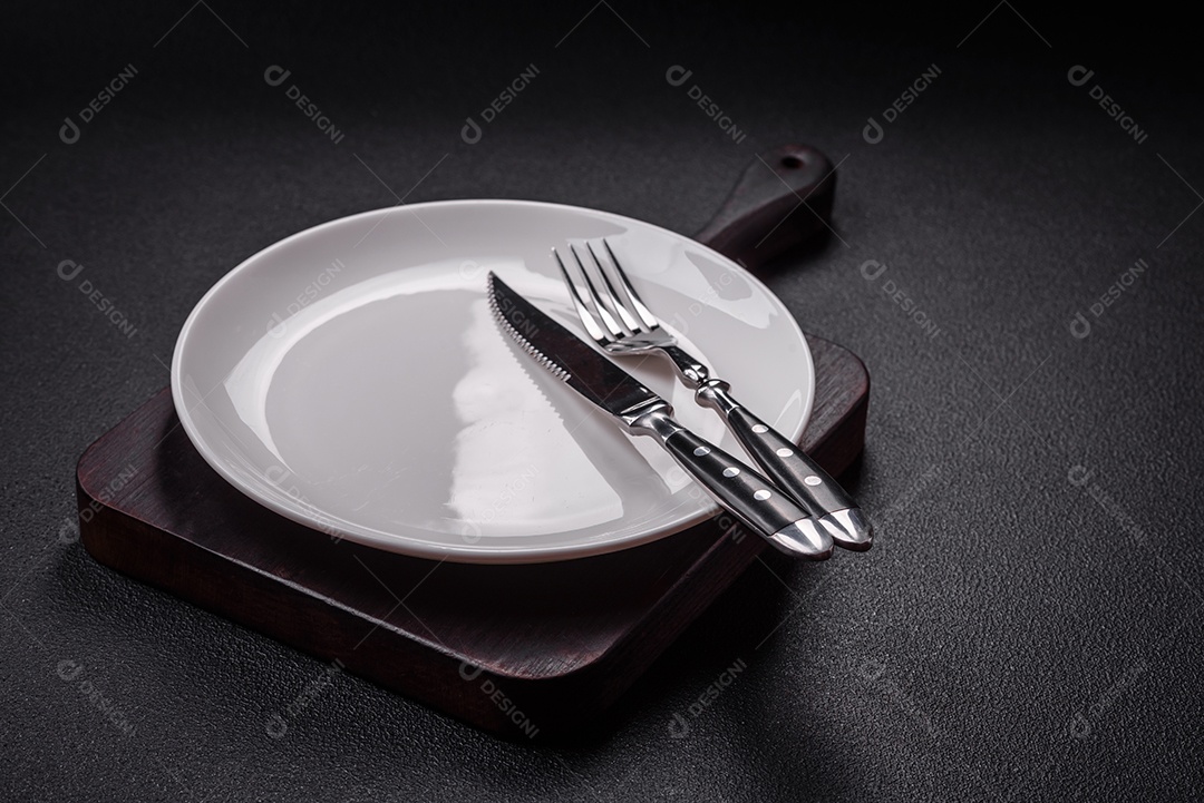 Placa cerâmica vazia e acidentada em um fundo de concreto texturizado. Utensílio de cozinha