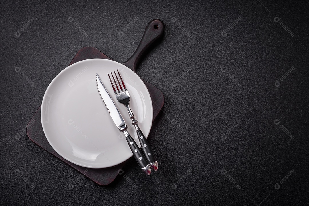 Placa cerâmica vazia e acidentada em um fundo de concreto texturizado. Utensílio de cozinha