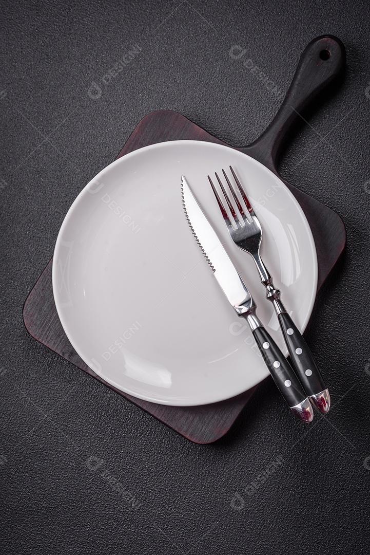 Placa cerâmica vazia e acidentada em um fundo de concreto texturizado. Utensílio de cozinha