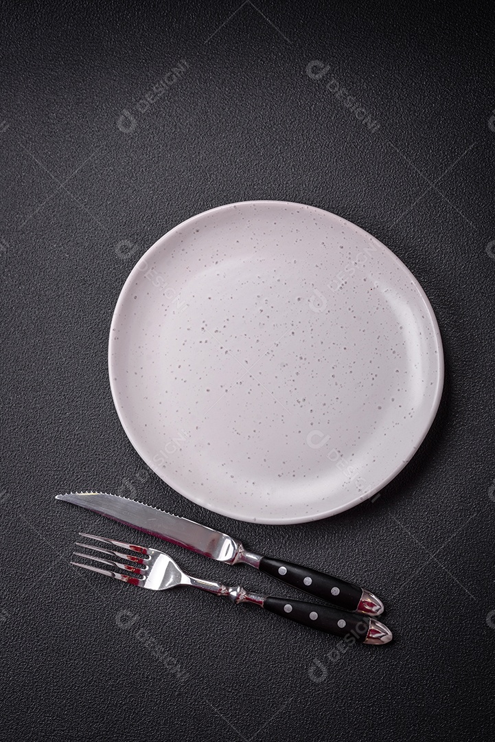 Placa cerâmica vazia e acidentada em um fundo de concreto texturizado. Utensílio de cozinha