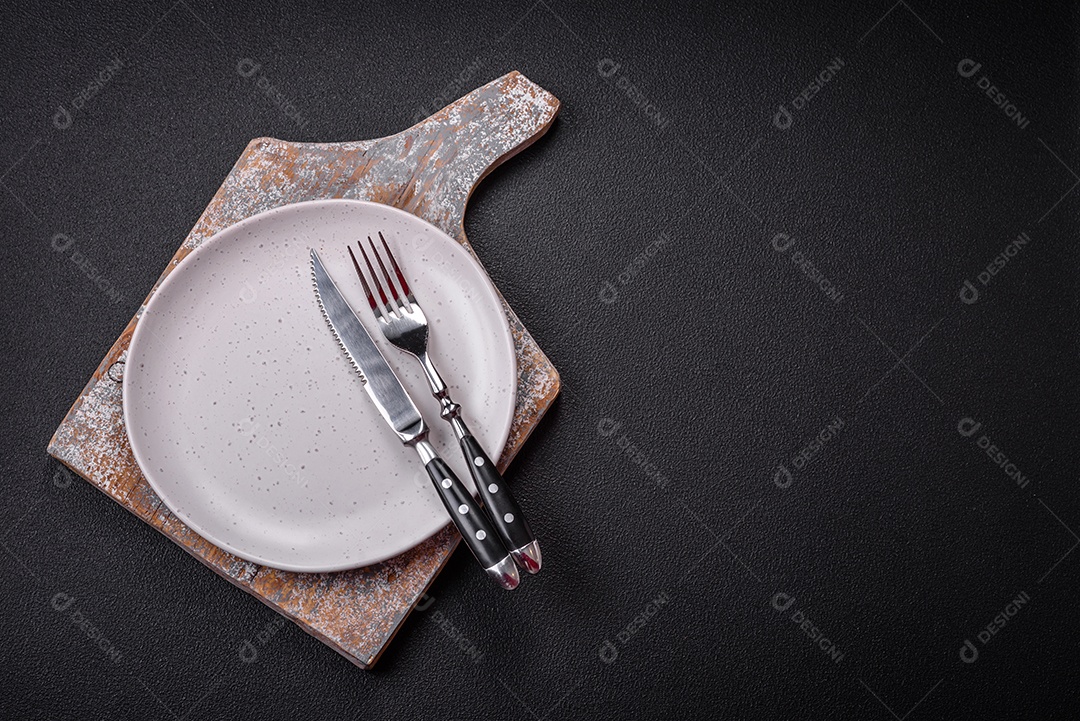 Placa cerâmica vazia e acidentada em um fundo de concreto texturizado. Utensílio de cozinha