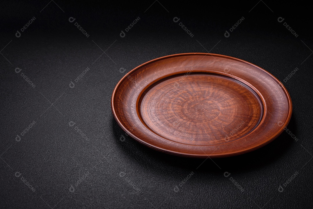 Placa cerâmica vazia e acidentada em um fundo de concreto texturizado. Utensílio de cozinha