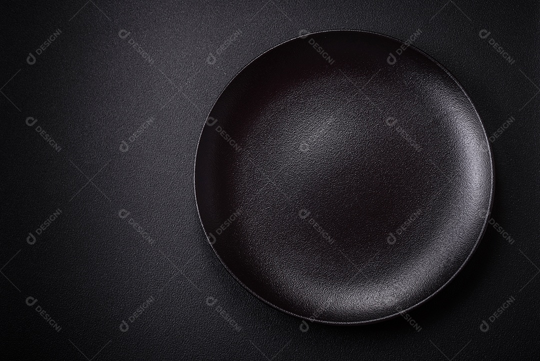 Placa cerâmica vazia e acidentada em um fundo de concreto texturizado. Utensílio de cozinha