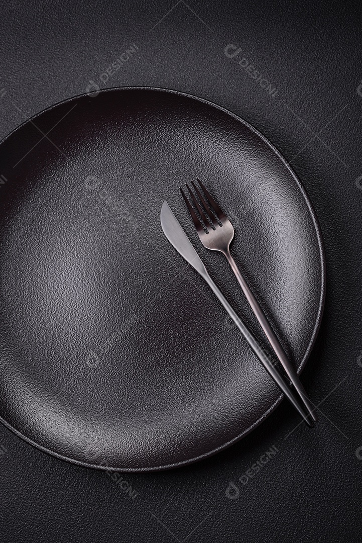 Placa cerâmica vazia e acidentada em um fundo de concreto texturizado. Utensílio de cozinha