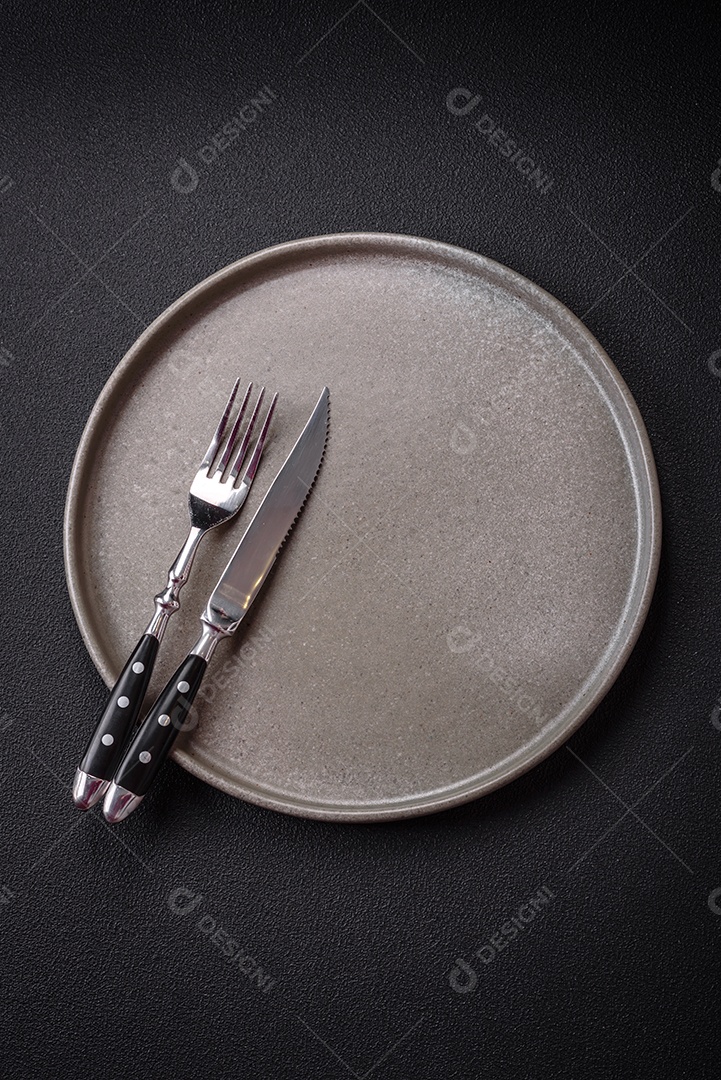 Placa cerâmica vazia e acidentada em um fundo de concreto texturizado. Utensílio de cozinha