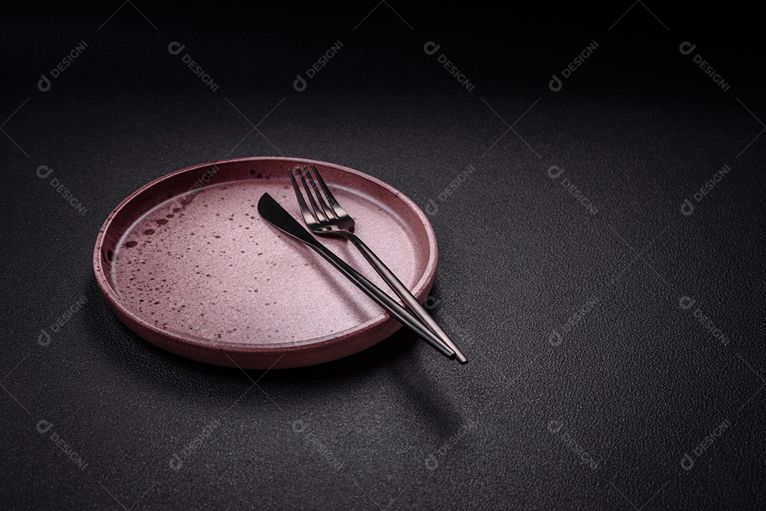 Placa cerâmica vazia e acidentada em um fundo de concreto texturizado. Utensílio de cozinha