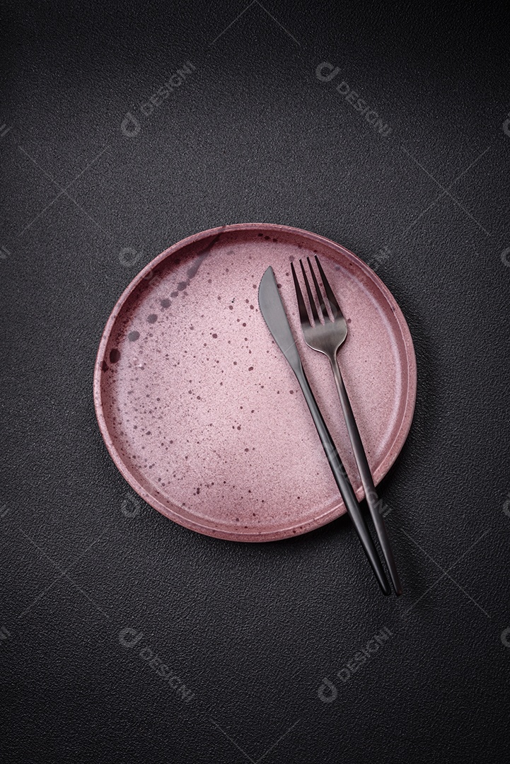 Placa cerâmica vazia e acidentada em um fundo de concreto texturizado. Utensílio de cozinha