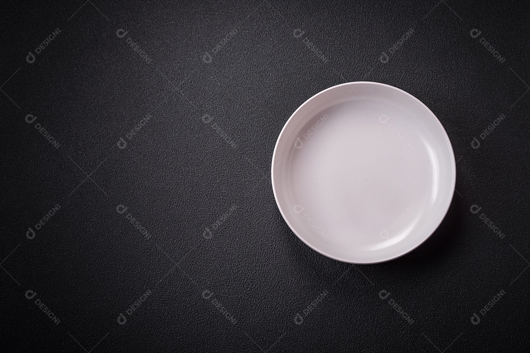 Placa cerâmica vazia e acidentada em um fundo de concreto texturizado. Utensílio de cozinha