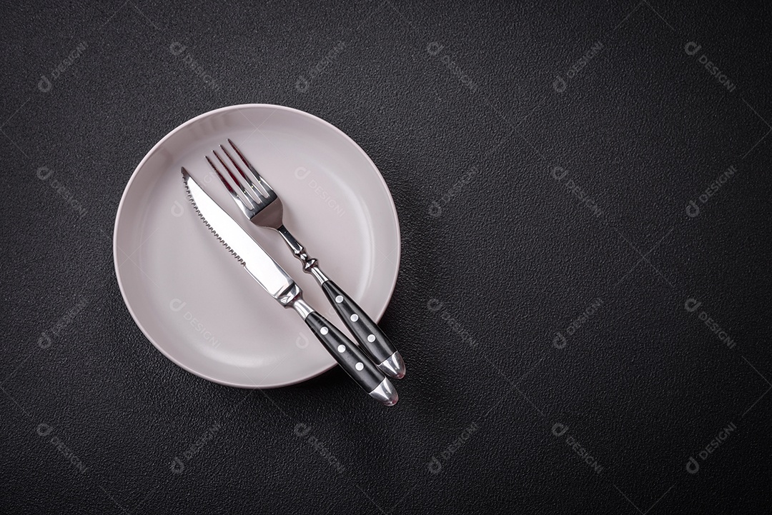 Placa cerâmica vazia e acidentada em um fundo de concreto texturizado. Utensílio de cozinha