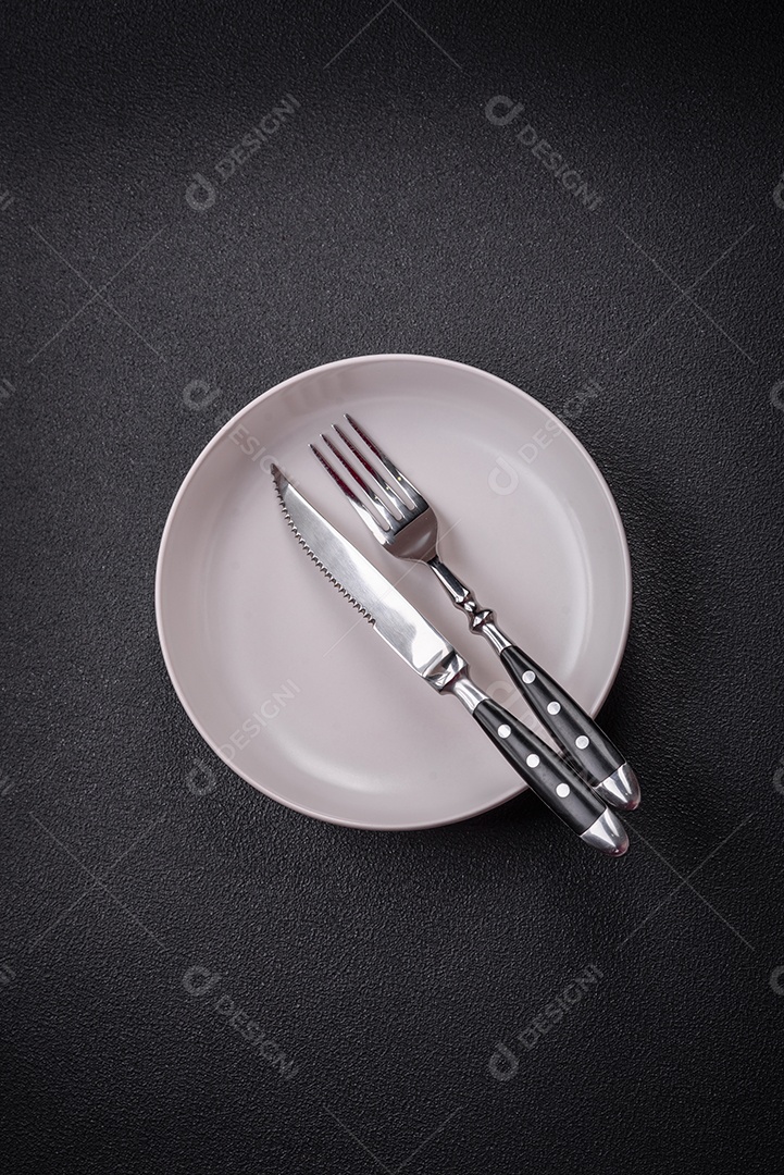 Placa cerâmica vazia e acidentada em um fundo de concreto texturizado. Utensílio de cozinha