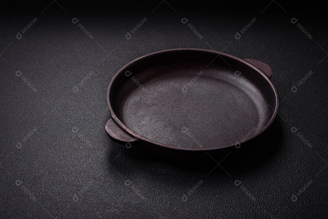 Placa cerâmica vazia e acidentada em um fundo de concreto texturizado. Utensílio de cozinha