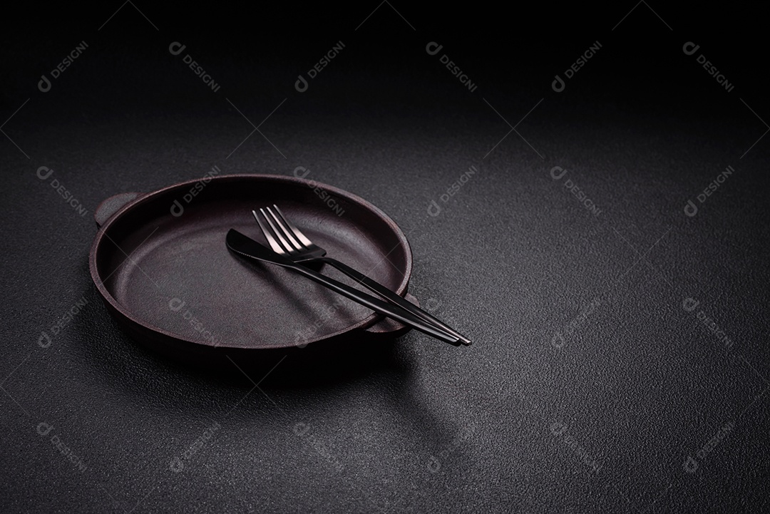 Placa cerâmica vazia e acidentada em um fundo de concreto texturizado. Utensílio de cozinha