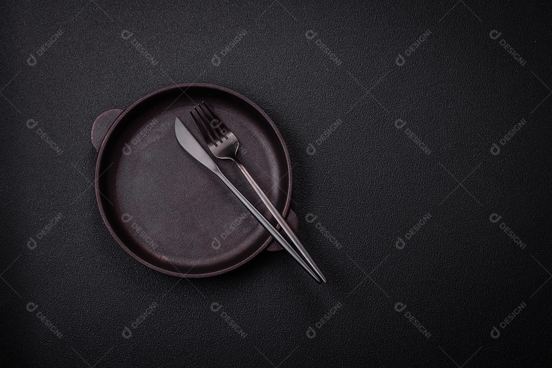 Placa cerâmica vazia e acidentada em um fundo de concreto texturizado. Utensílio de cozinha