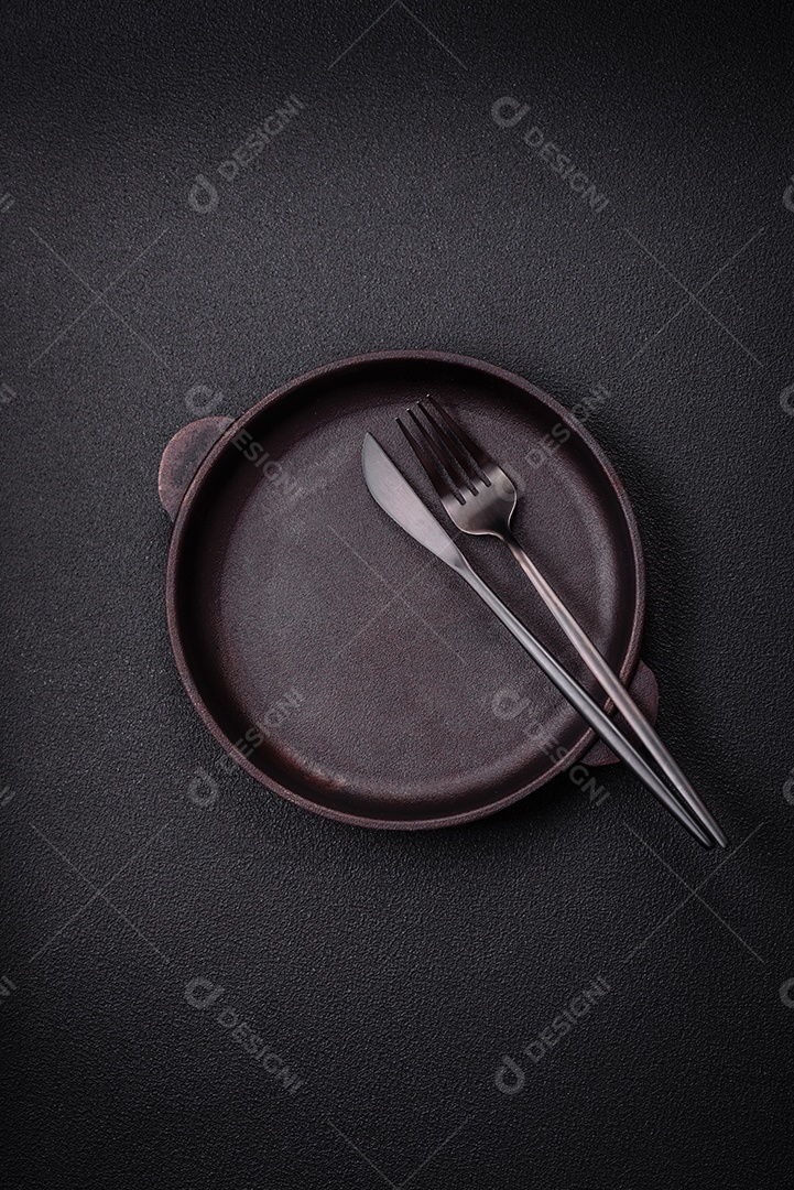 Placa cerâmica vazia e acidentada em um fundo de concreto texturizado. Utensílio de cozinha