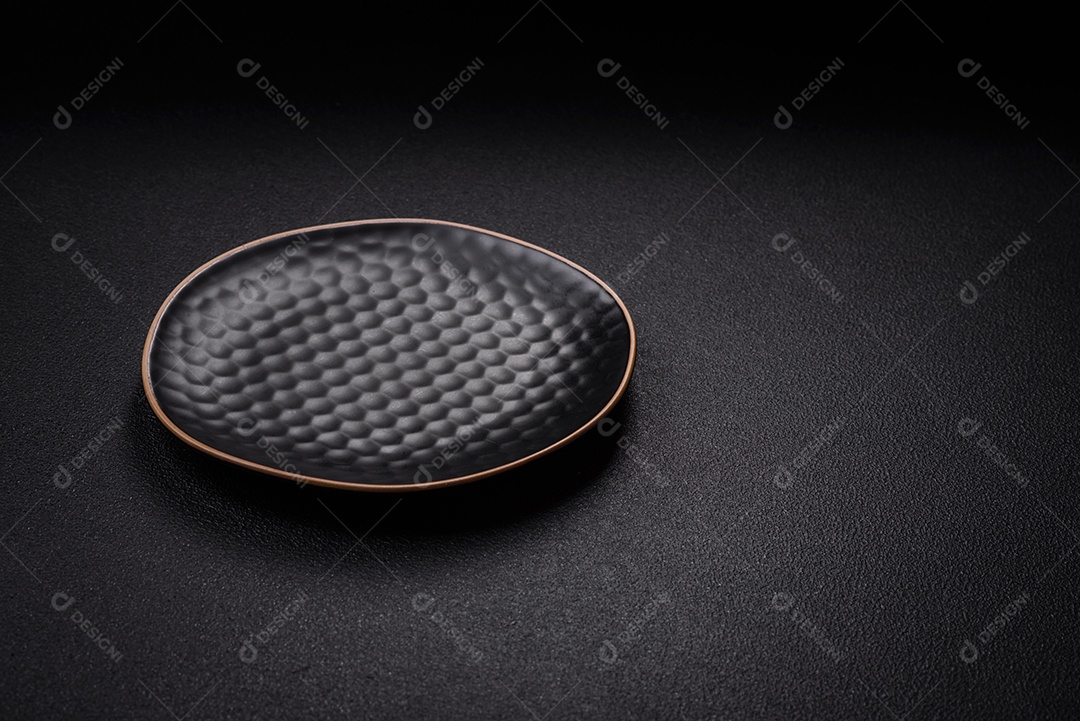 Placa cerâmica vazia e acidentada em um fundo de concreto texturizado. Utensílio de cozinha