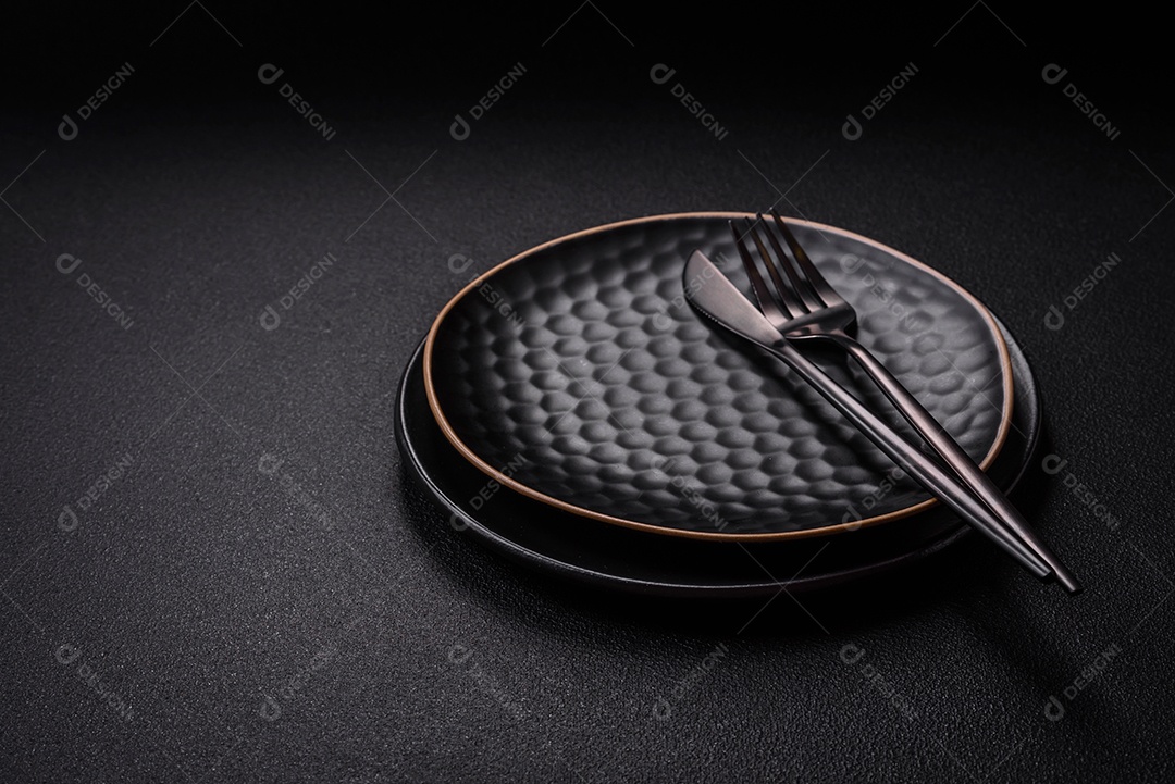 Placa cerâmica vazia e acidentada em um fundo de concreto texturizado. Utensílio de cozinha