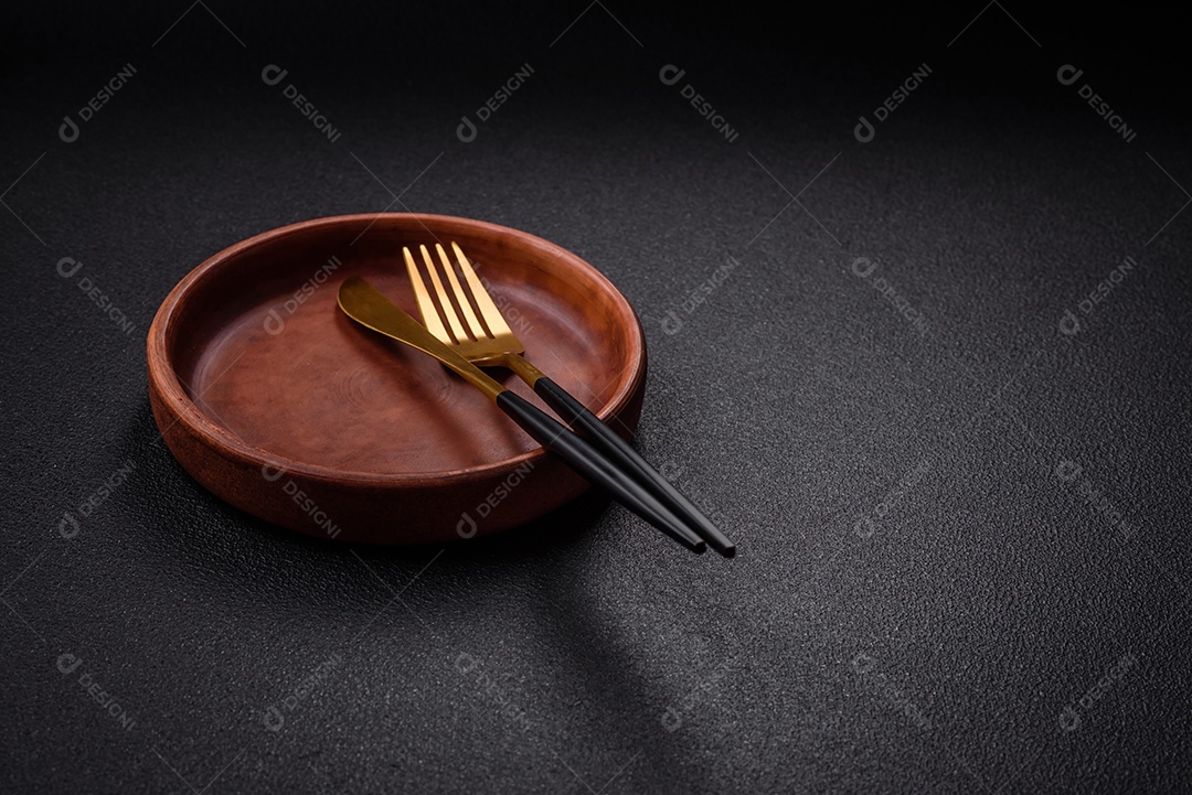 Placa cerâmica vazia e acidentada em um fundo de concreto texturizado. Utensílio de cozinha