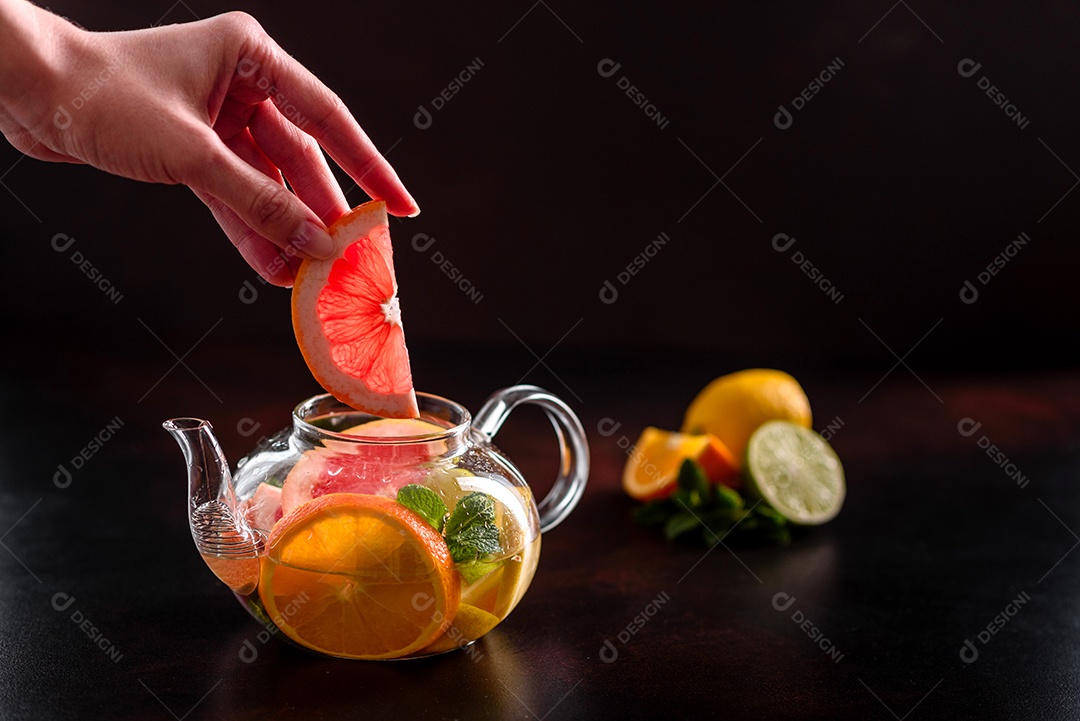 Chá de frutas quentes com limão, hortelã, laranja, limão e toranja em um lindo bule de vidro