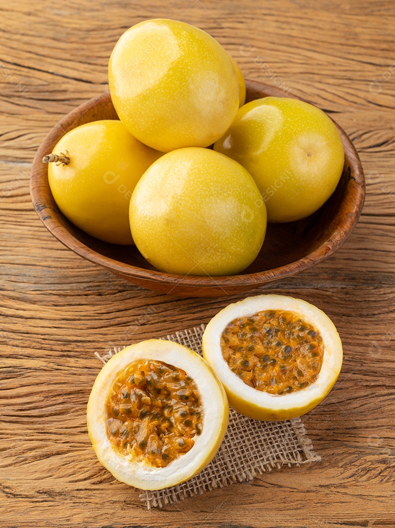 Maracujá em uma tigela com frutas cortadas sobre a mesa de madeira