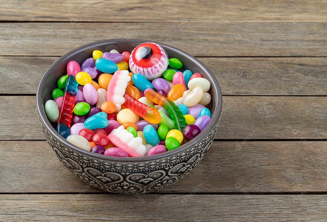Doces coloridos variados em uma tigela sobre a mesa de madeira