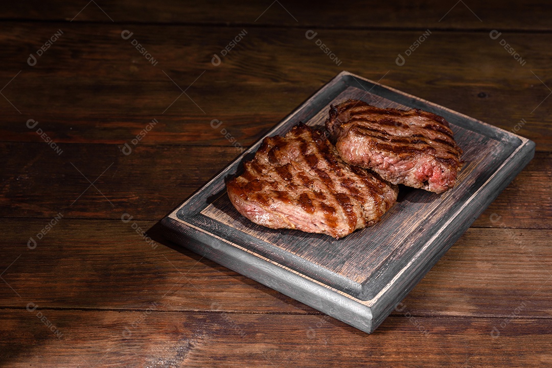 Bife fresco, suculento e delicioso em um fundo escuro. Prato de carne com especiarias e ervas