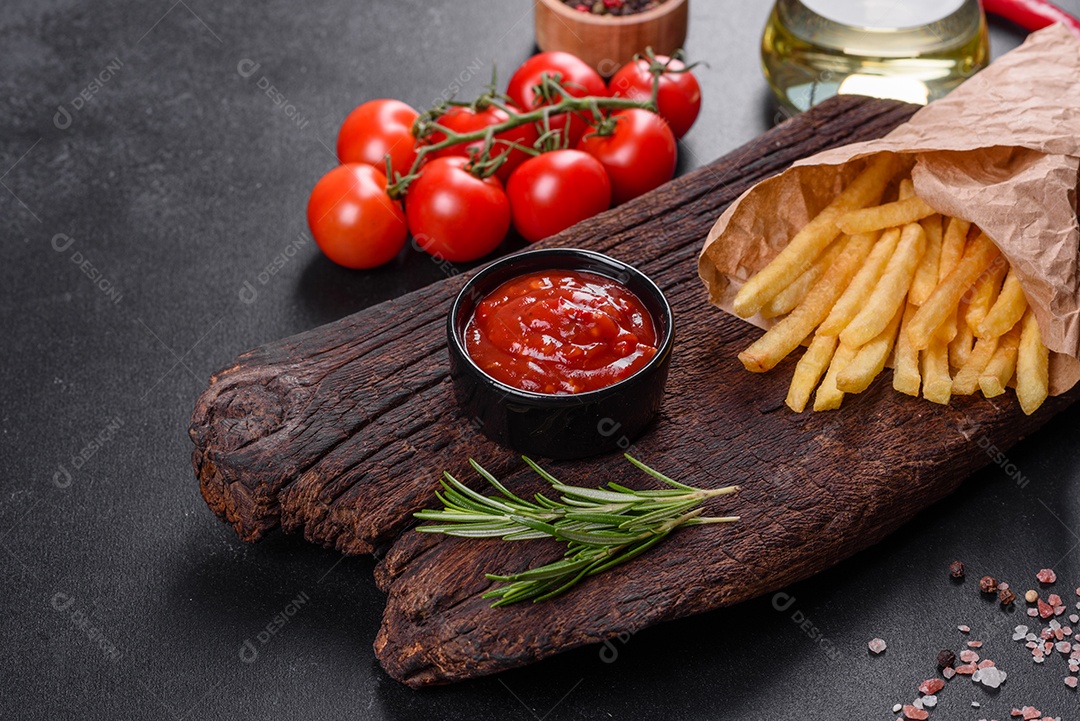 Frescas saborosas batatas fritas e molho vermelho em uma tábua de madeira. Alimentos não saudáveis